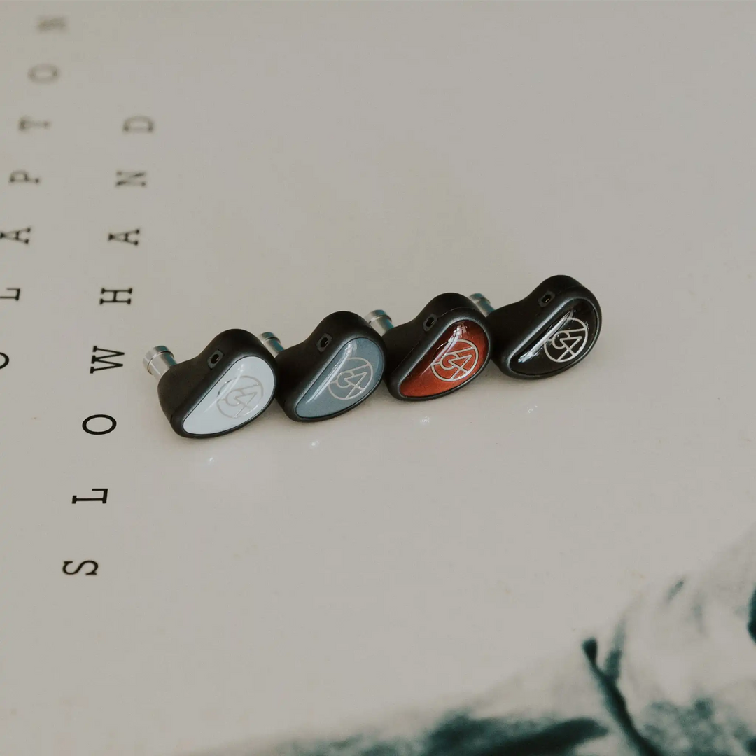 64 Audio Aspire Series IEMs lined up at front left 3 quarter angle sitting on vinyl record