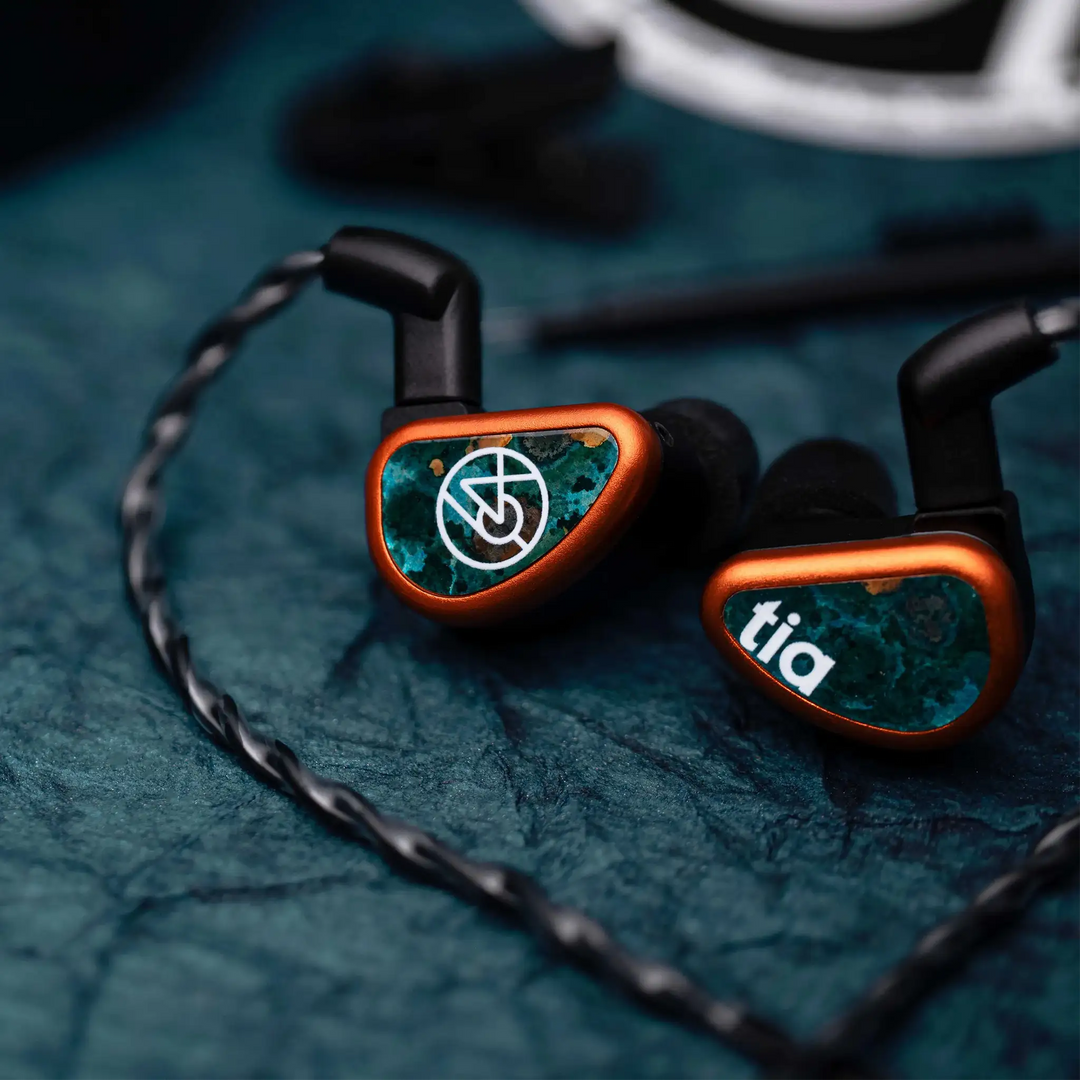 64 Audio Fourte IEMs faceplate closeup sitting on blue backdrop with cable attached