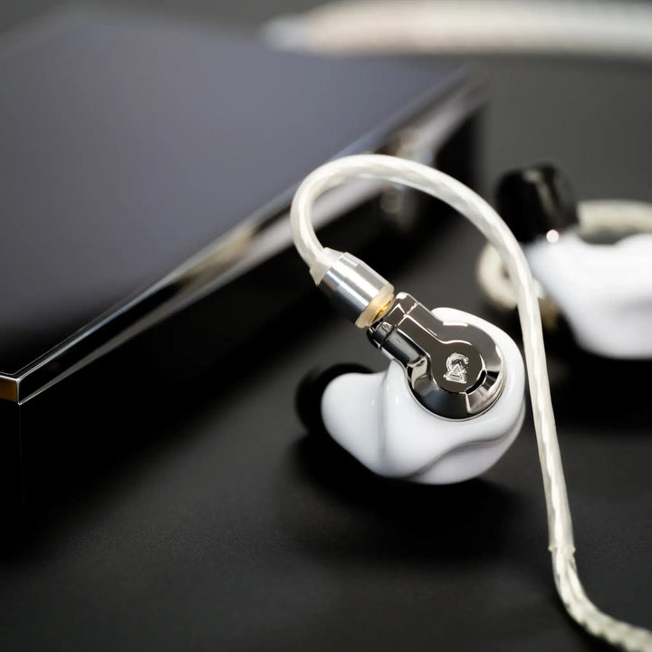 Campfire Audio Cascara MV3 over black surface with attached cable and DAP Bokeh