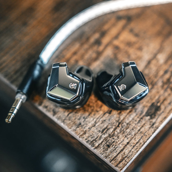 Campfire Audio Supermoon front warm dramatic highlighting reflective faceplates on wood table from Bloom Audio gallery