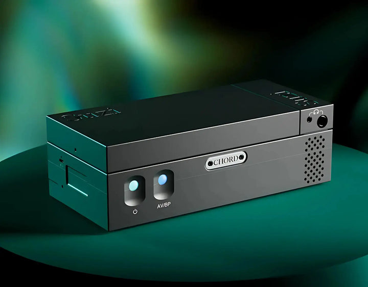 Chord Electronics Suzi Stereo Amplifier sitting front left 3 quarter angle on round stand with green lighting