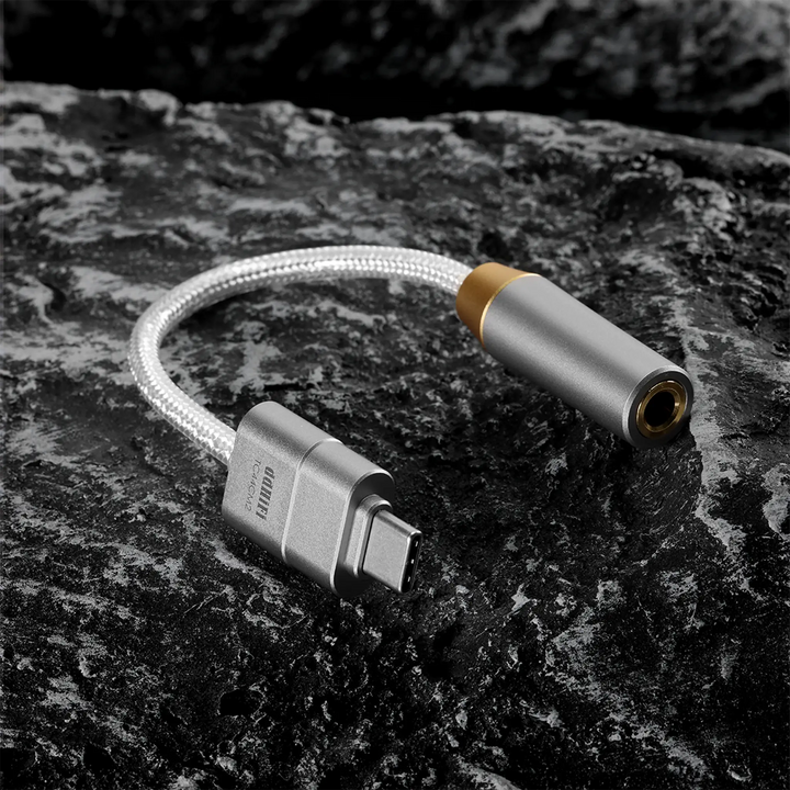 ddHiFi TC44CM2 DAC dongle sitting in c-shape on black rock background