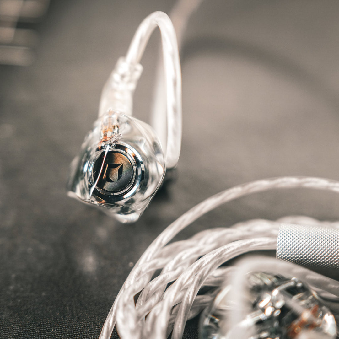 DITA Audio Project M single earphone extreme closeup with attached coiled, stock cable