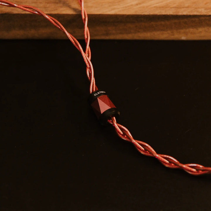 Eletech x Bloom Crimson IEM cable closeup of y-split on black background with wooden plank