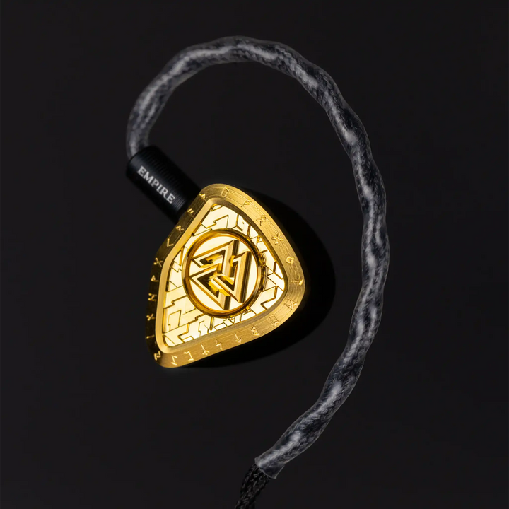 Empire Ears Odin MKII left IEM floating front right 3 quarter angle closeup of 24K gold faceplate with cable attached on black background
