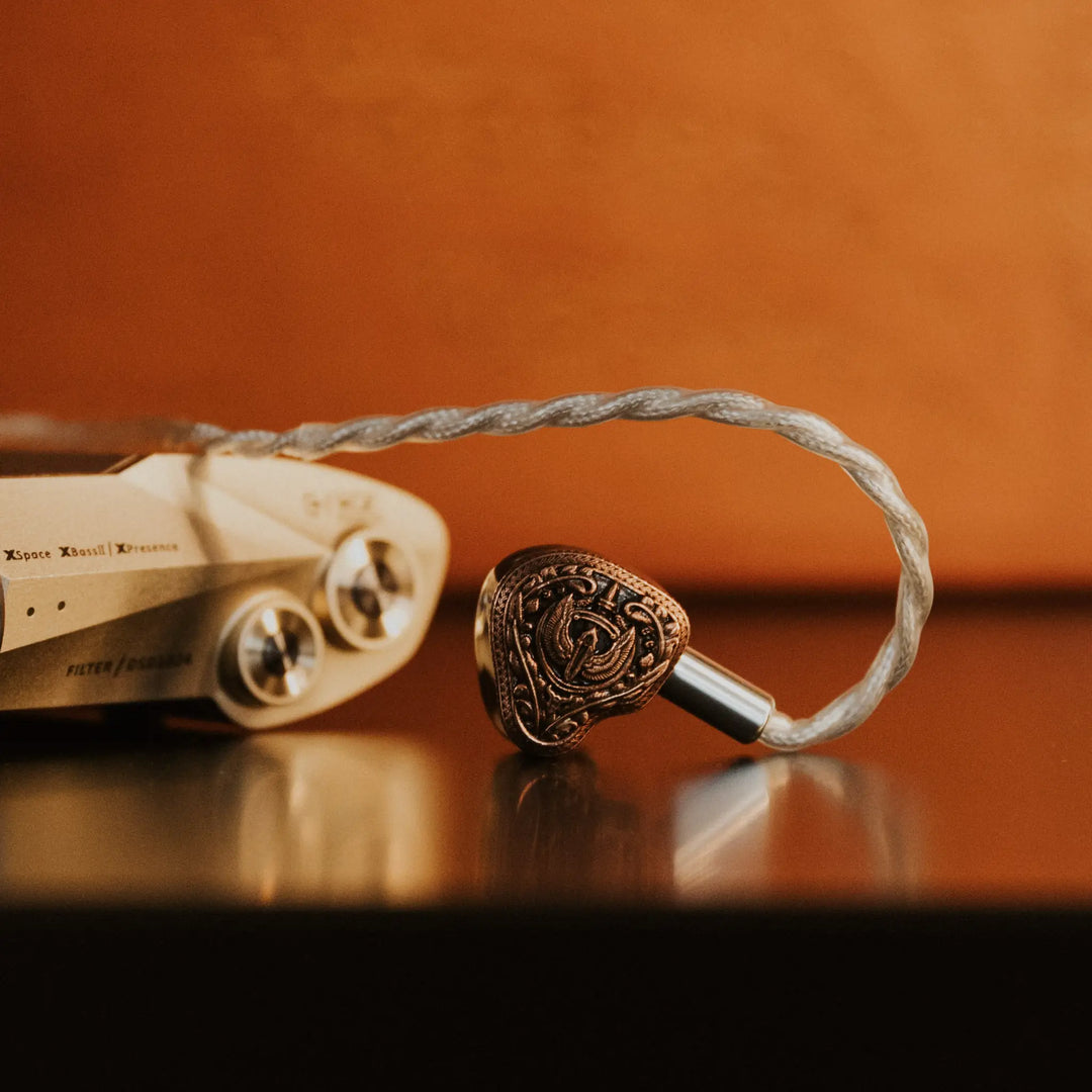 Closeup FlipEars Aegis earphone with attached stock cable next to iFi Valkyrie DAC