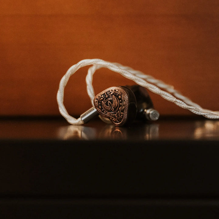 Closeup FlipEars Aegis earphones with attached stock cable and copper color background