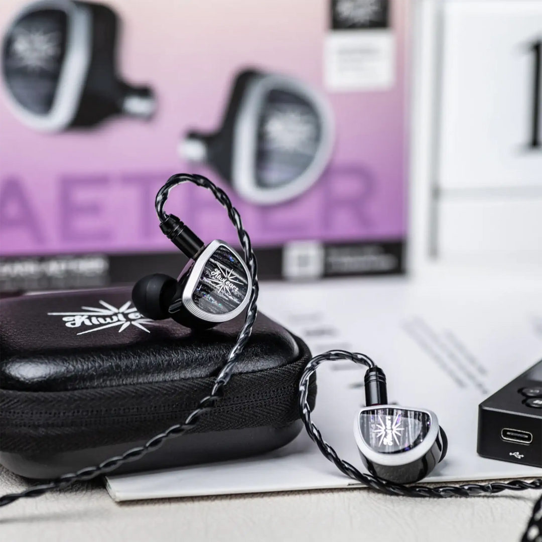 Kiwi Ears Aether IEMs sitting on black case and white table with device and product box in background