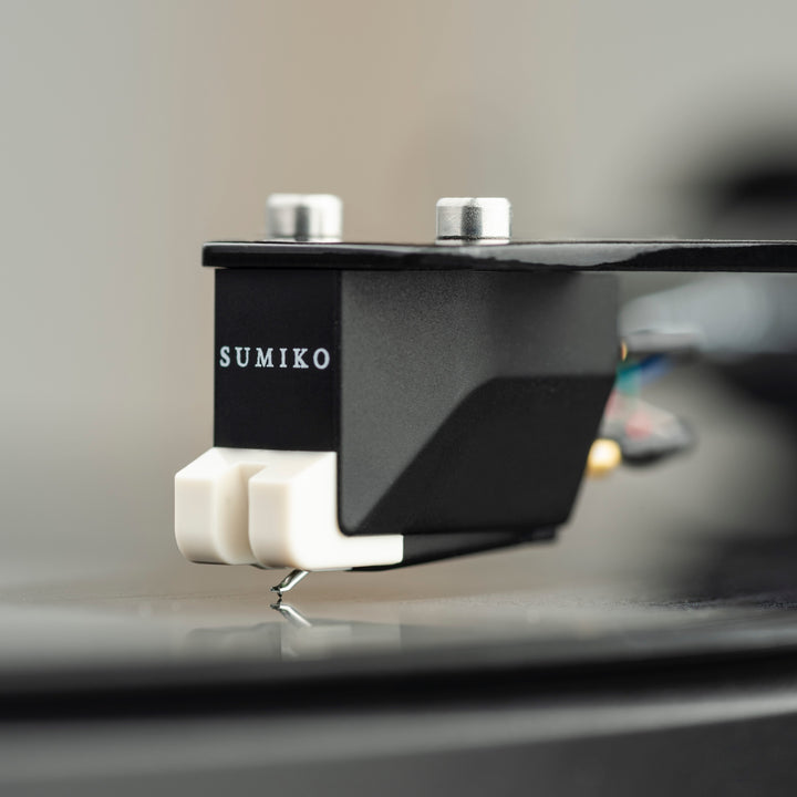 Extreme closeup Sumiko phono cartridge resting on disc