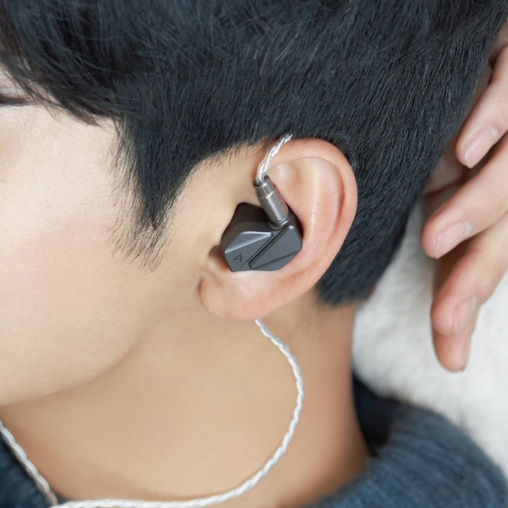 Astell&Kern AK ZERO2 with attached stock cable inserted into human ear