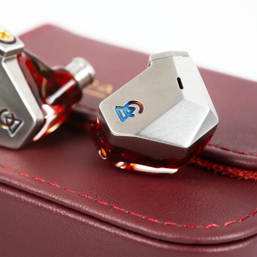 Campfire Audio Grand Luna IEMs sitting on top of red hard case front iem in focus second iem cut off on left side of frame