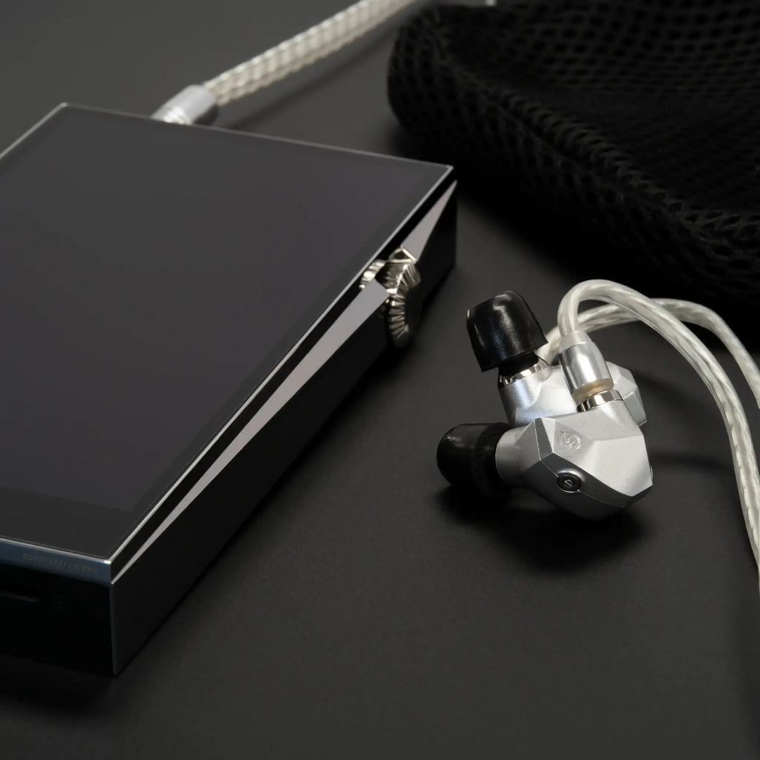 Campfire Audio Taurus sitting on black surface with ear tips and DAP