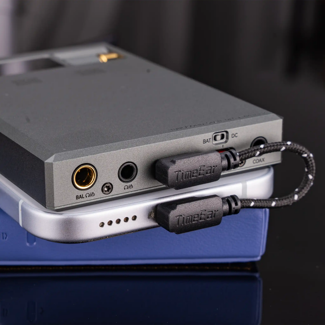 Cayin RU9 DAC and amp lying on top of leather case and smartphone showing magnetic back panel and L-shaped USB cable
