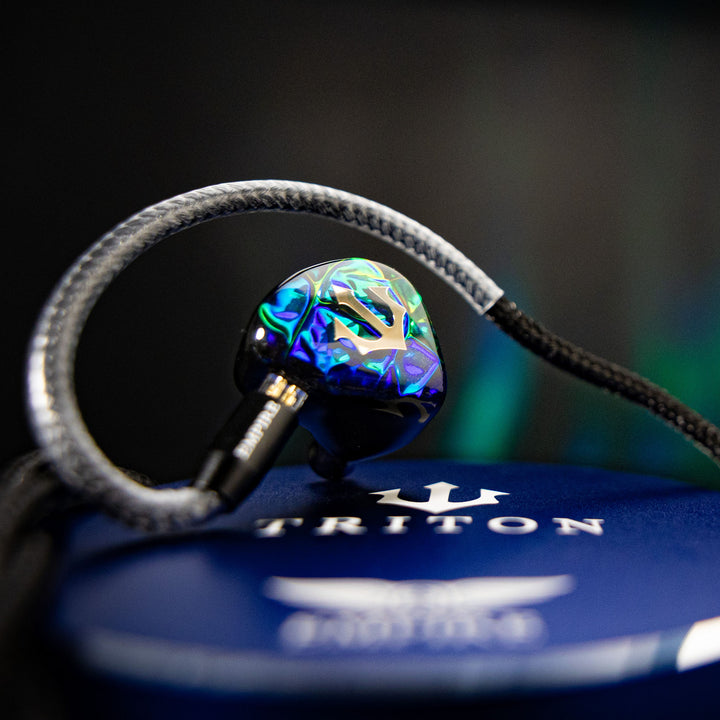 Empire Ears Triton closeup with attached stock cable over blue case