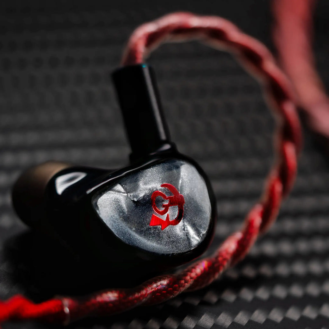 FATfreq x HBB Deuce closeup left earphone with attached blood cable over black herringbone background