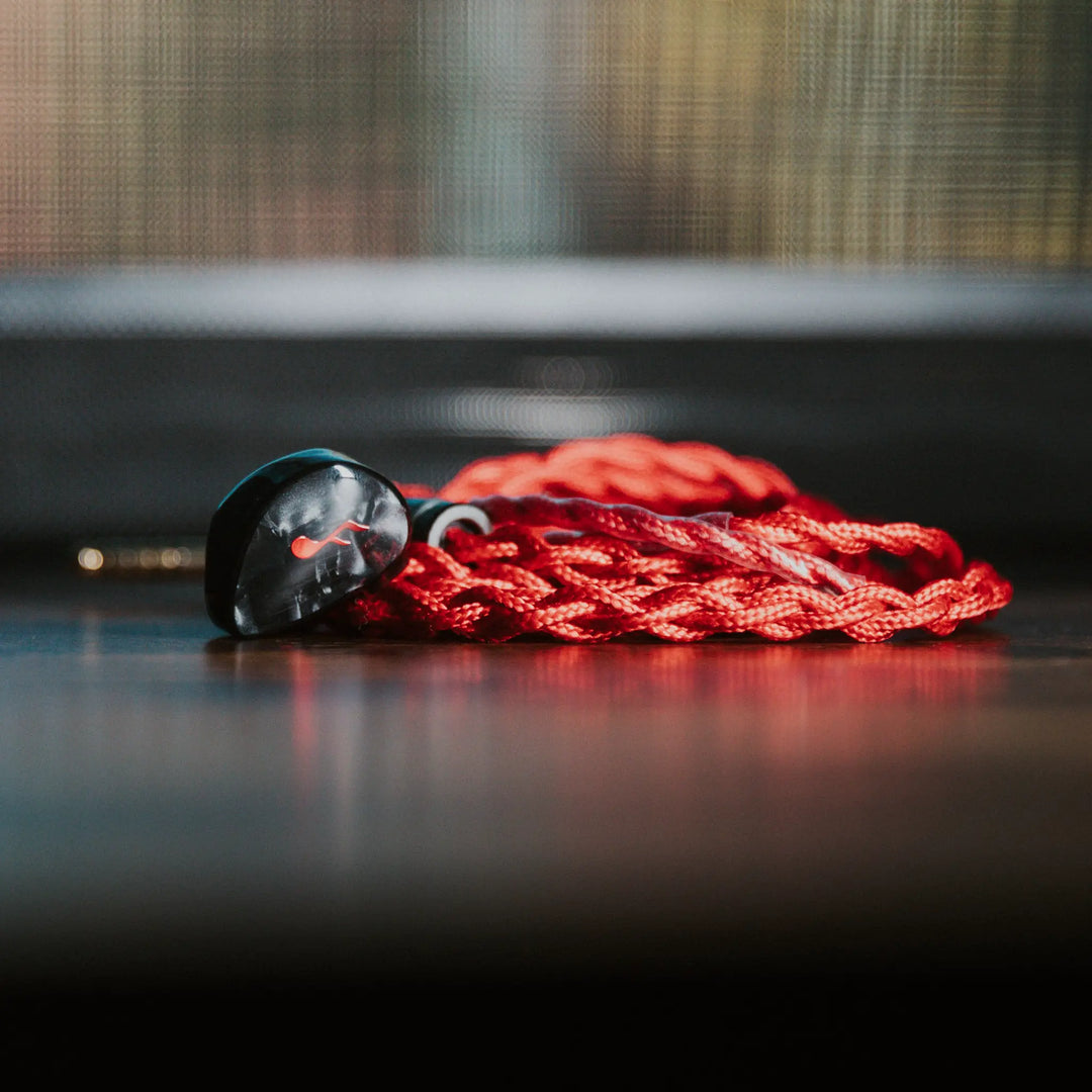 FATfreq x HBB Deuce closeup eye level with attached coiled stock red blood cable on smooth surface