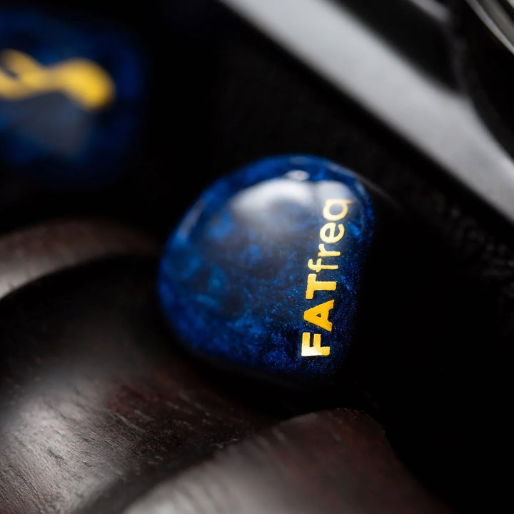 FATfreq Maestro Mini left earphone closeup shell over wood carved pedestal