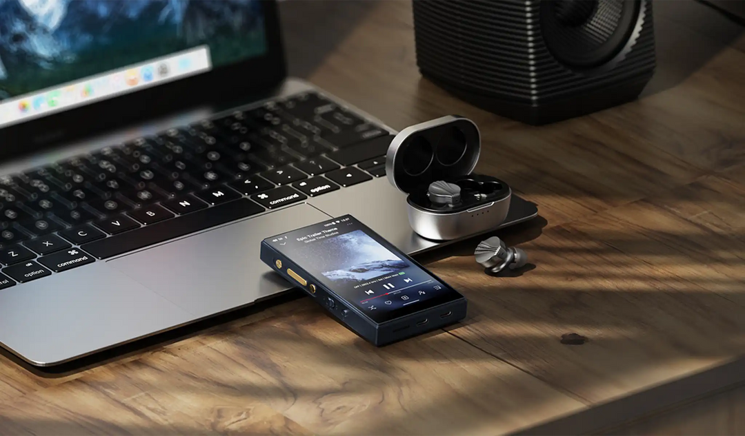 FiiO M21 DAP blue lying face up on open macbook with TWS earphones sitting in open case on wooden desk