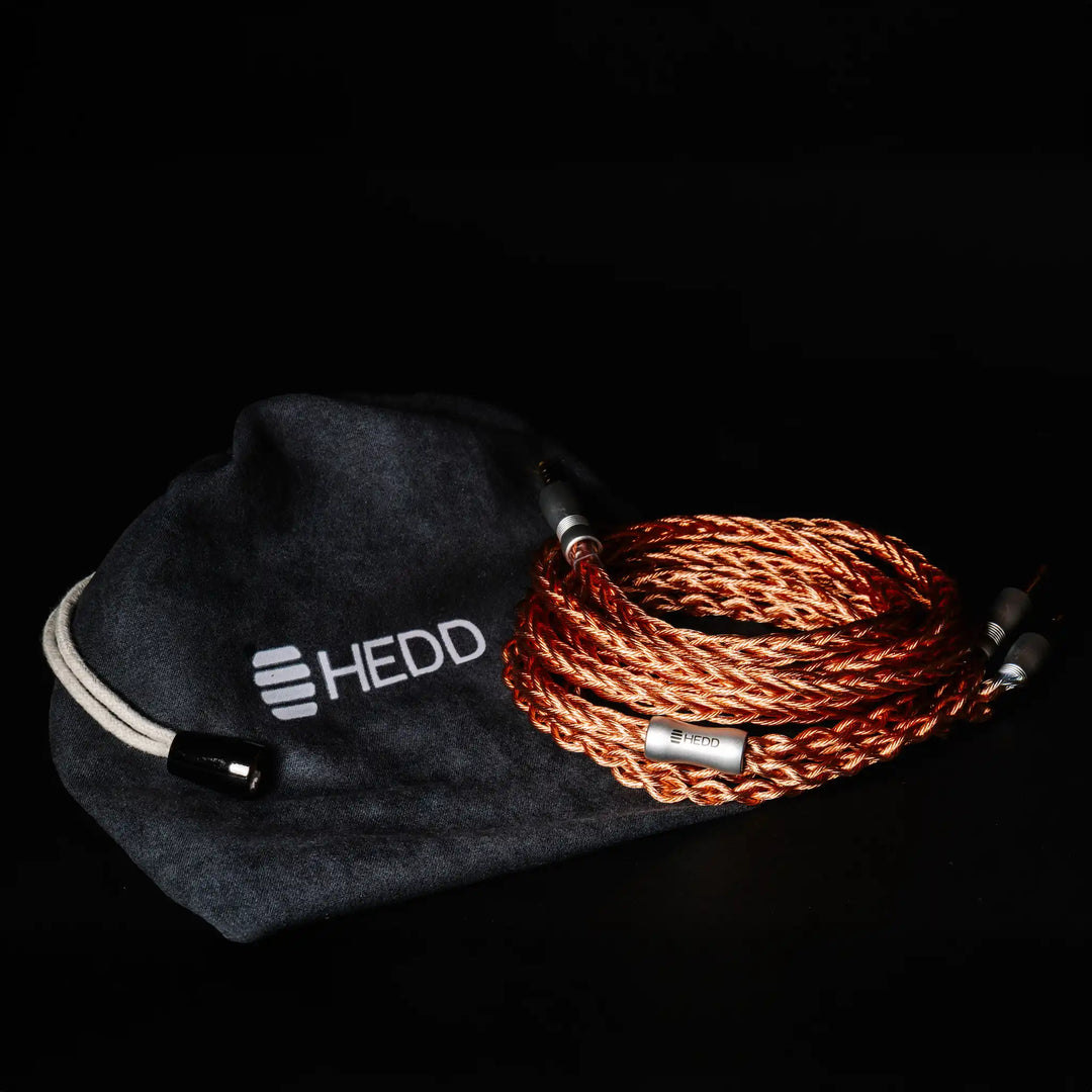 HEDD Audio HEDDphone TWO cable coiled sitting on top of HEDD carrying pouch on black background