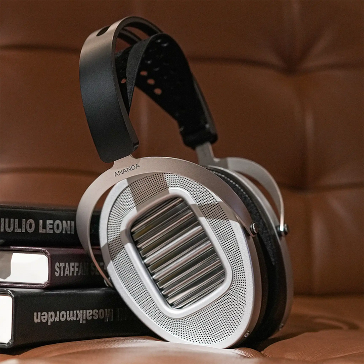 HIFIMAN Ananda Unveiled headphones sitting on brown leather couch right ear cup view leaning on stack of books