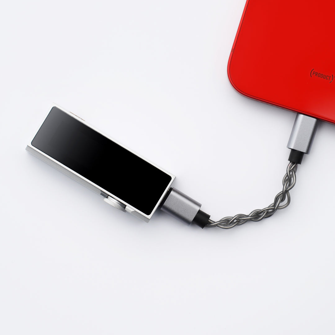 iBasso DC07Pro silver dongle with attached stock cable connected to red iPhone