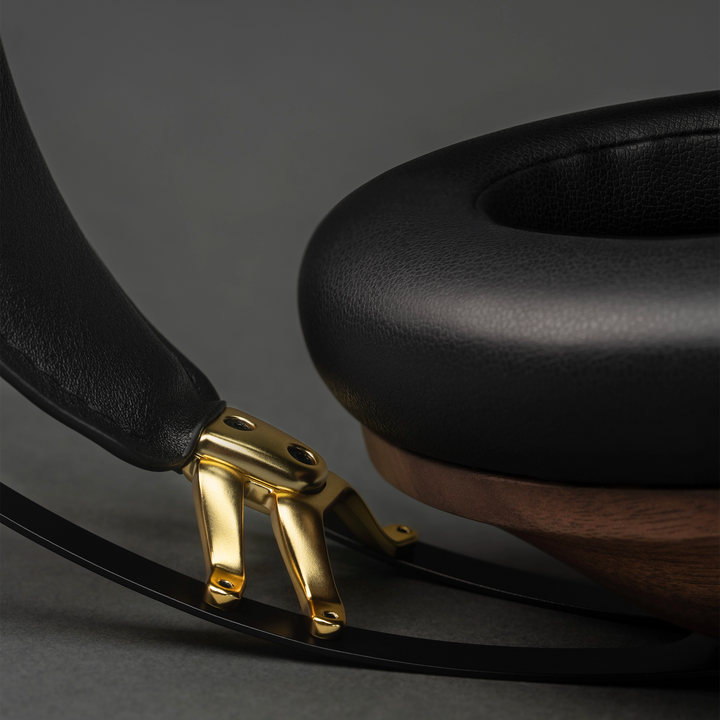 Meze 99 Classics 2nd Gen headphones extreme closeup of gold hinge and frame on grey background