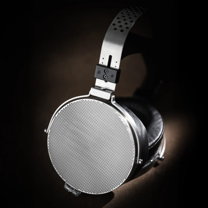 Moondrop Para 2 headphones sitting on right earcup, left earcup closeup on brown textured backdrop