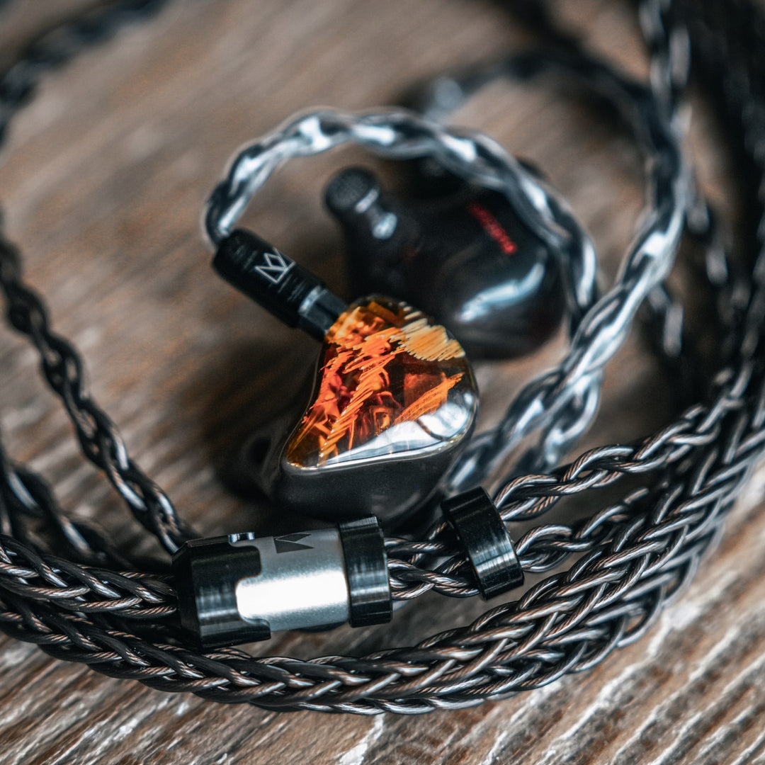 Noble Audio Spartacus IEM with attached coiled stock cable over wood block shelf