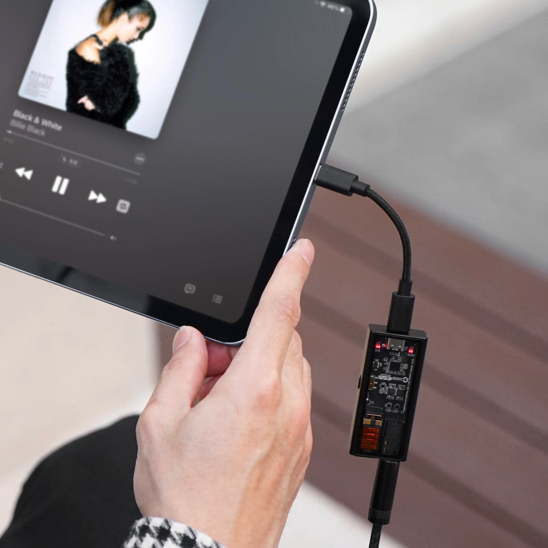 Questyle M15i with attached headphone cable connected to iPad in human hand