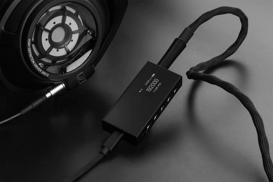 Questyle M18i dac/amp plugged into Sennheiser headphone on black background