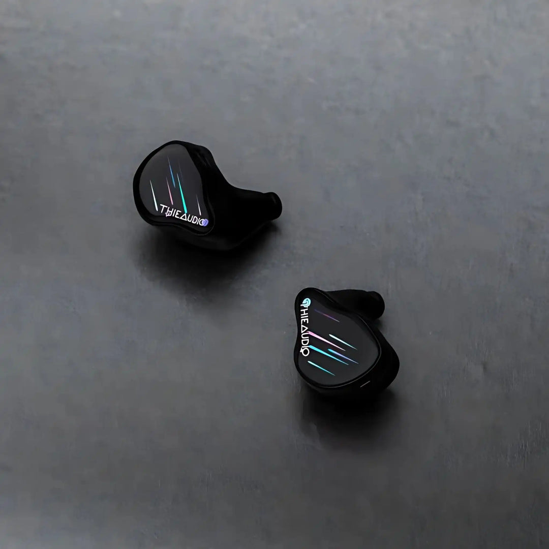 Thieaudio Monarch MKIV IEMs with Stellashot faceplate sitting diagonally face up on grey background