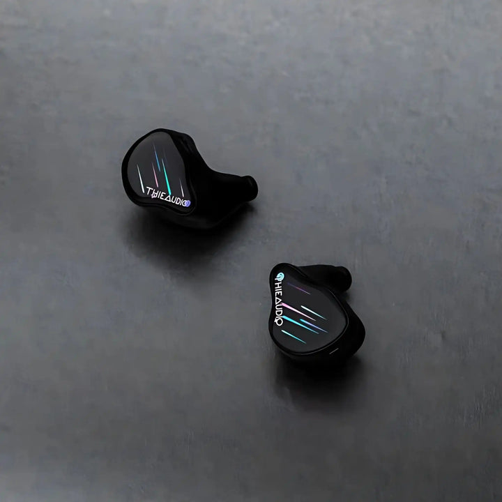 Thieaudio Monarch MKIV IEMs with Stellashot faceplate sitting diagonally face up on grey background