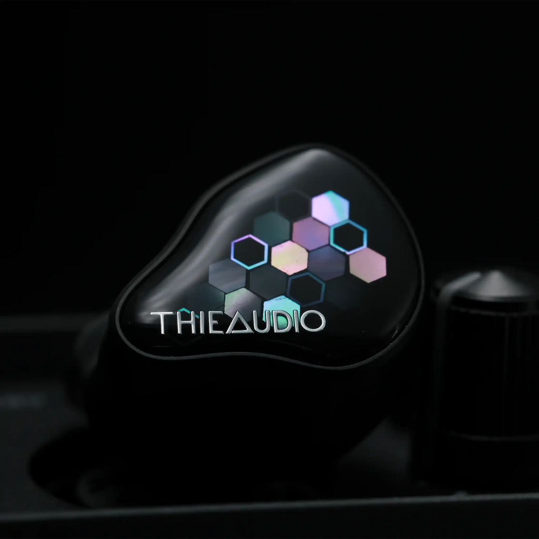 Thieaudio Monarch MKIV IEM sitting front center on black desktop amp