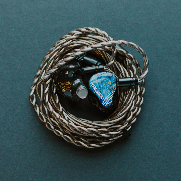 Thieaudio Oracle MK3 with attached stock coiled cable over teal background