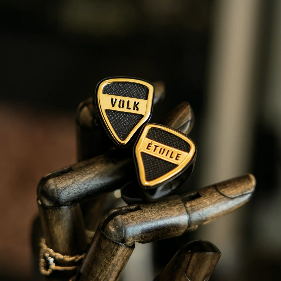 Volk Audio Etoile IEMs sitting diagonally on fake wooden hand front view