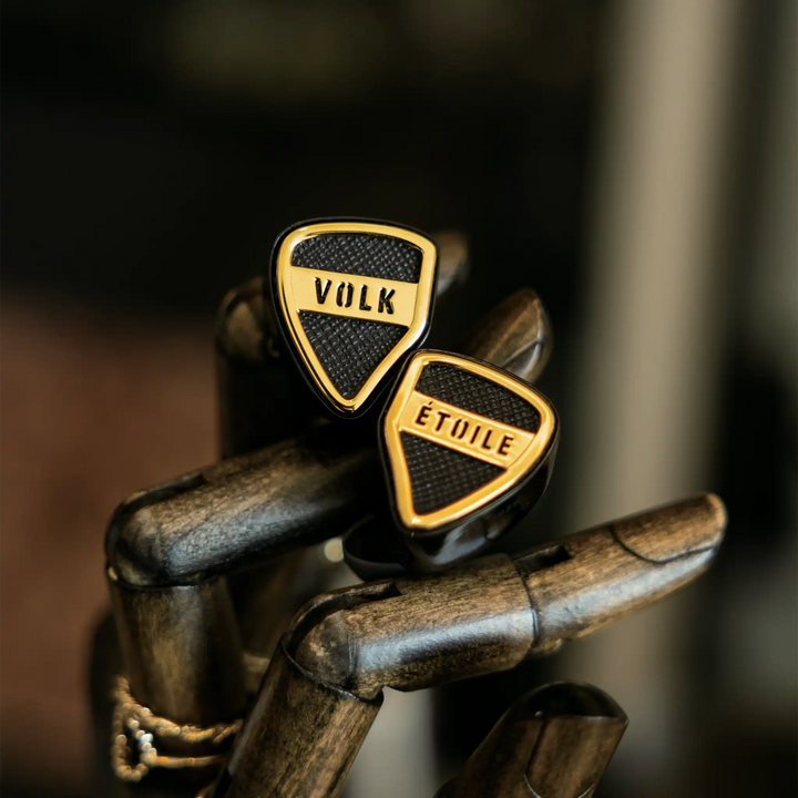 Volk Audio Etoile IEMs sitting diagonally on fake wooden hand front view