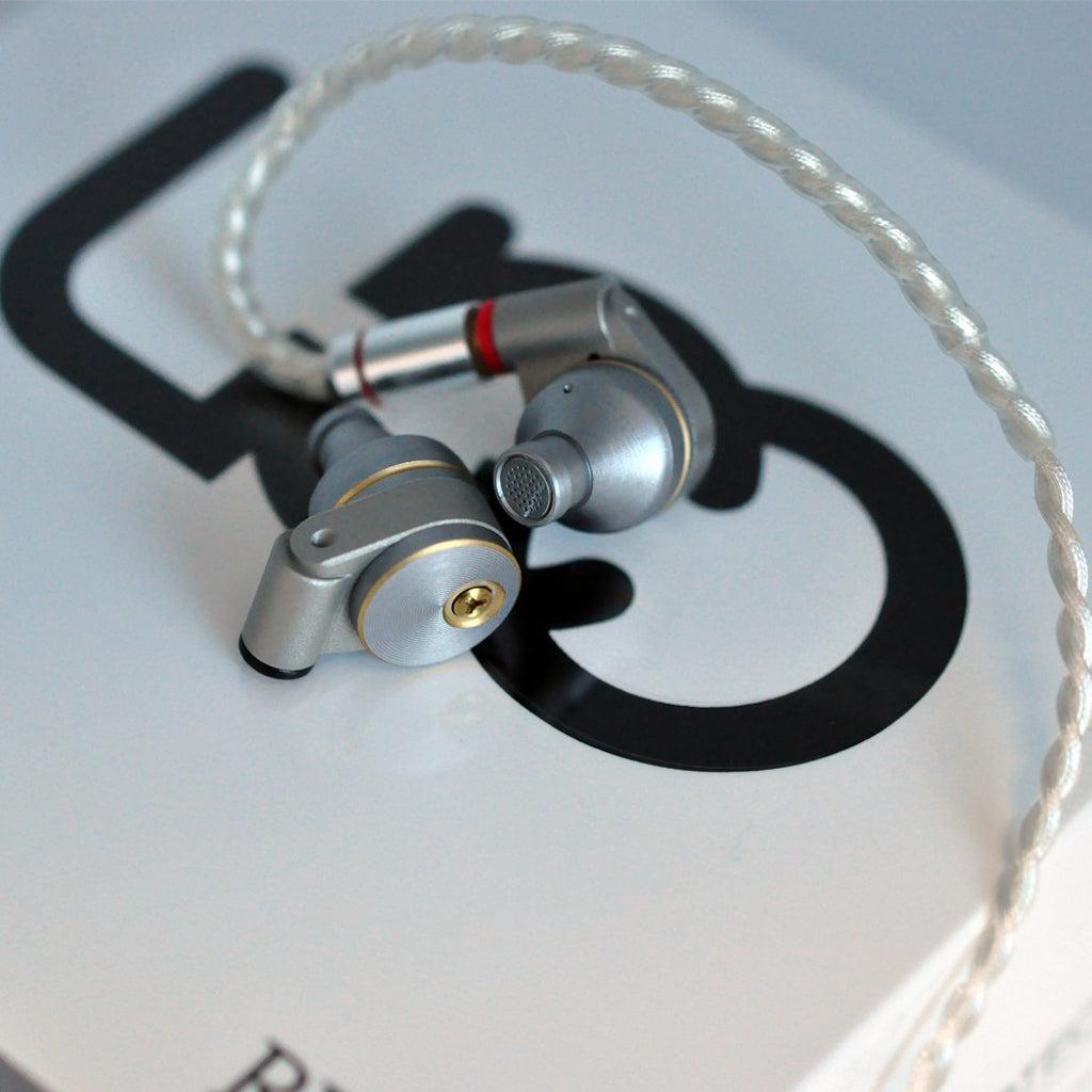 Ucotech RE-2 earphones with one attached cable over UCO brand logo